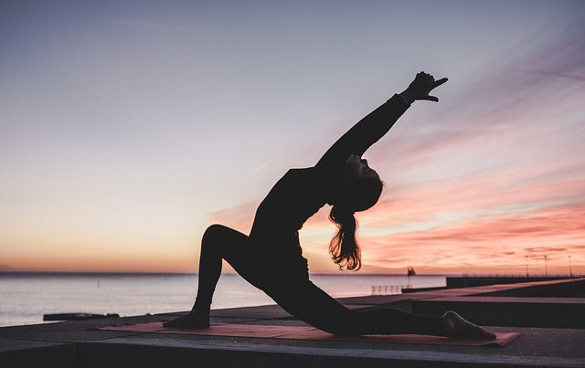 Femme faisant du yoga en extérieur avec un coucher de soleil
