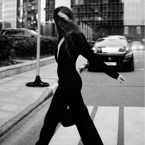 Silhouette féminine en tailleur structuré dans un éclairage clair-obscur, posture droite et aura de puissance.