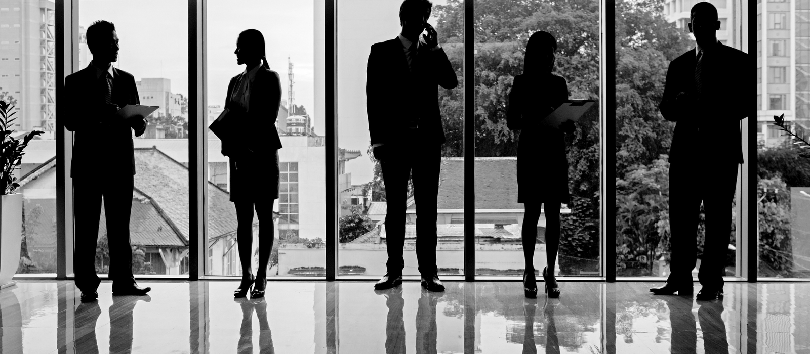 Femme en veste tailleurs structurée et homme en costume, debout, posture droite - vêtements professionnels pensés pour la durée d'une journée de travail.