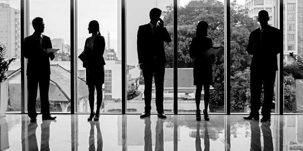 Femme en veste tailleurs structurée et homme en costume, debout, posture droite - vêtements professionnels pensés pour la durée d'une journée de travail.