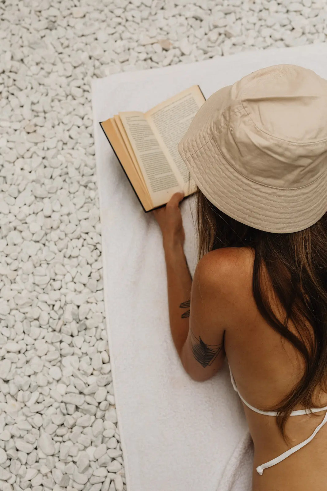 femme allonger sur la plage lisant un livre 