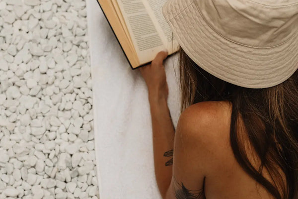 femme allonger sur la plage lisant un livre 