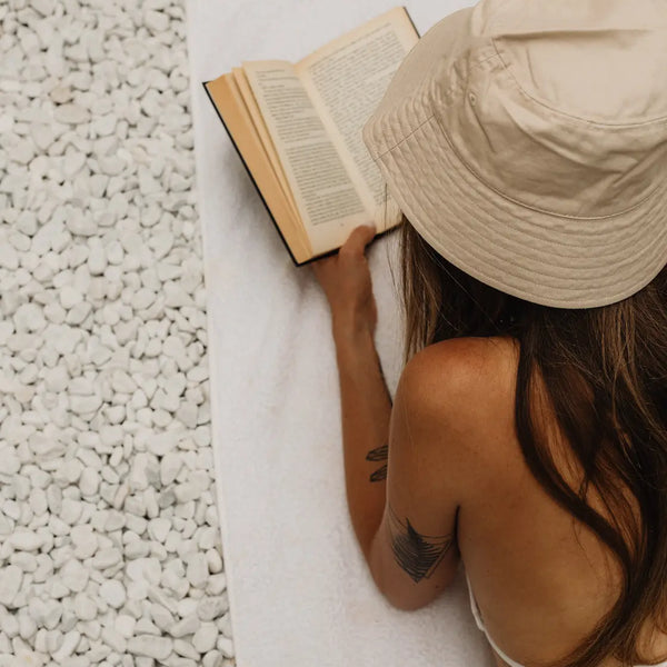 femme allonger sur la plage lisant un livre 