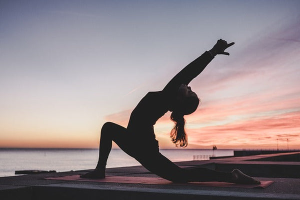 Femme faisant du yoga en extérieur avec un coucher de soleil